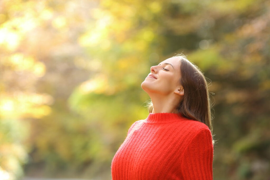 A Woman in red breathing fresh air in autumn in a forest