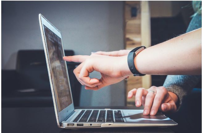 Two people on a laptop looking up the guided selling definition. 